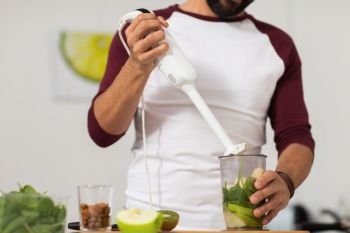 healthy eating, vegetarian food, diet and people concept - man with blender and fruits cooking at home kitchen. man with blender and fruit cooking at home kitchen