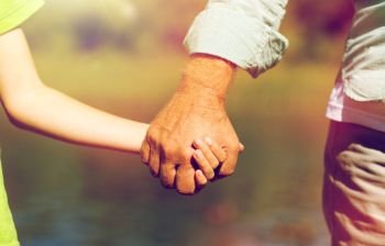 family, generation, support and people concept - senior man and child holding hands. senior man and child holding hands