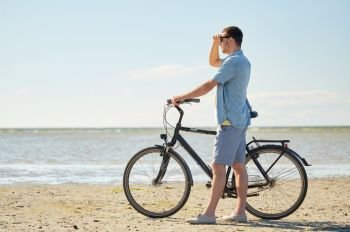 people, leisure and lifestyle concept - happy young man with bicycle on beach . happy young man with bicycle on beach 
