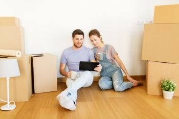 mortgage, people and real estate concept - happy couple with boxes and tablet pc computer moving to new home. couple with boxes and tablet pc moving to new home