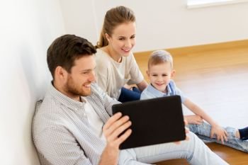 mortgage, people, housing and real estate concept - happy family with tablet pc computer moving to new home. happy family with tablet pc moving to new home