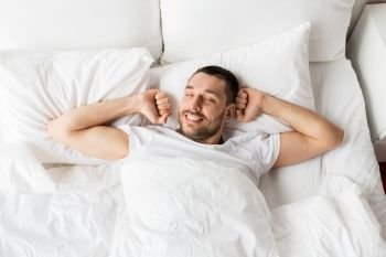 people, bedtime and rest concept - man lying in bed at home. man lying in bed at home