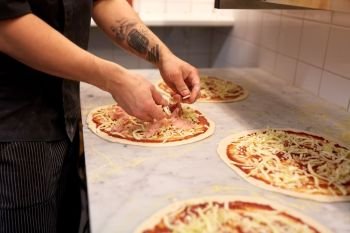 food cooking, culinary and people concept - cook or baker hands adding champignons to pizza at pizzeria. cook hands adding champignons to pizza at pizzeria