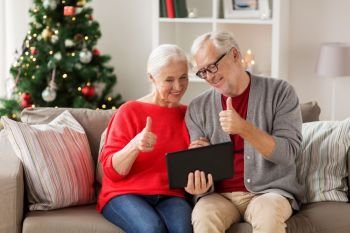 christmas, holidays, communication and people concept - happy smiling senior couple with tablet pc computer having video chat at home. happy senior couple with tablet pc at christmas