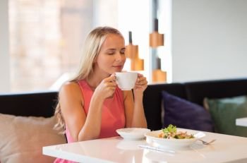 people and leisure concept - happy woman drinking coffee and eating salad for lunch at restaurant. woman eating and drinking coffee at restaurant