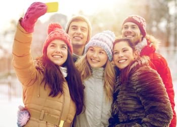 people, friendship, technology, winter and leisure concept - happy friends taking selfie with smartphone outdoors. happy friends taking selfie with smartphone