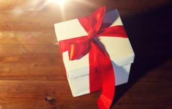 christmas, holidays, presents, new year and celebration concept - close up of gift box with red bow on wooden floor from top. close up of christmas  gift box on wooden floor