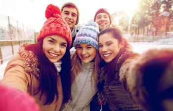 people, friendship, technology, winter and leisure concept - happy friends taking selfie with smartphone or camera outdoors. happy friends taking selfie with smartphone
