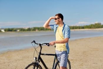 people, leisure and lifestyle concept - happy young man with bicycle on summer beach. happy man with bicycle on summer beach