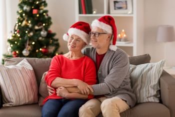 christmas, holidays and people concept - happy smiling senior couple in santa hats at home. happy senior couple in santa hats at christmas