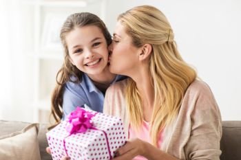 people, holidays and family concept - happy girl giving birthday present to mother at home. girl giving birthday present to mother at home