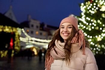 holidays and people concept - beautiful happy young woman at christmas market in winter evening. happy young woman at christmas market in winter