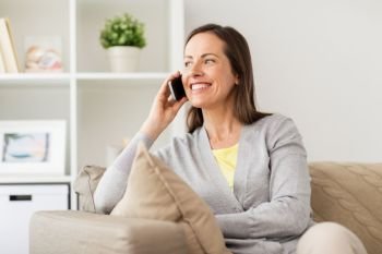 people, technology and communication concept - happy woman calling on smartphone at home. happy woman calling on smartphone at home