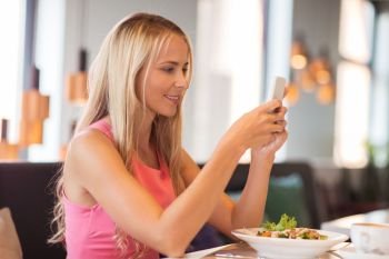 eating, technology, communication and leisure concept - happy woman with smartphone and salad for lunch at restaurant. happy woman with smartphone eating at restaurant