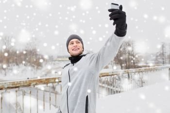 fitness, sport, people, exercising and healthy lifestyle concept - young man taking selfie with smartphone in winter . man taking selfie with smartphone in winter 