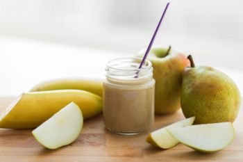 baby food, healthy eating and nutrition concept - glass jar with apple, pear and banana fruit puree on wooden board. jar with fruit puree or baby food