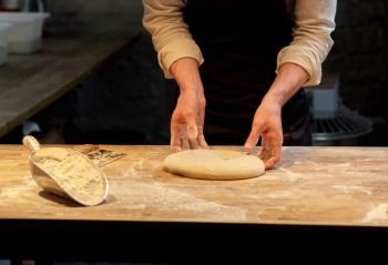 food cooking, baking and people concept - chef or baker making dough at bakery. chef or baker cooking dough at bakery