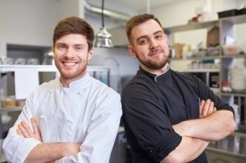 cooking, profession and people concept - happy male chef and cook at restaurant kitchen. happy smiling chef and cook at restaurant kitchen