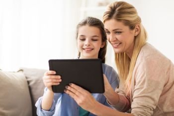 people, family and technology concept - happy girl and mother with tablet pc computer at home. happy family with tablet pc at home