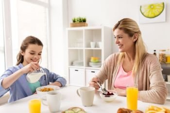 food, healthy eating, family and people concept - happy mother and daughter having breakfast at home kitchen. happy family having breakfast at home kitchen