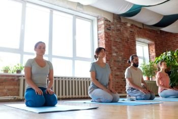 fitness, yoga and healthy lifestyle concept - group of people meditating in seated pose at studio. group of people meditating at yoga studio