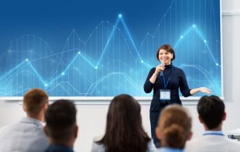 business, statistics and people concept - smiling businesswoman or lecturer with microphone and diagram chart on projection screen talking to group of students at conference presentation or lecture. group of people at business conference or lecture
