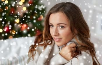 winter holidays and people concept - happy young woman with plaid over christmas tree at home and snow. happy young woman with plaid at home for christmas