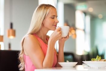 people and leisure concept - happy woman drinking coffee and eating at restaurant. woman eating and drinking coffee at restaurant