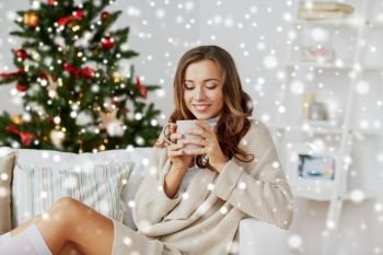 christmas, holidays and people concept - happy young woman with cup of coffee or tea at home over snow. happy woman with cup of tea at home for christmas