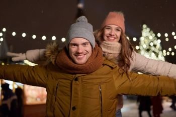 winter holidays and people concept - happy young couple dating and having fun at christmas market in evening. happy couple having fun at christmas market