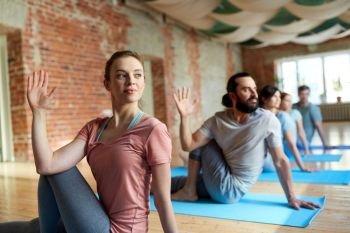 fitness, yoga and healthy lifestyle concept - group of people doing half lord of the fishes pose in gym or studio. group of people doing yoga at studio