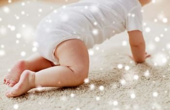 childhood, babyhood and people concept - little baby boy or girl crawling on floor over snow. little baby in diaper crawling on floor