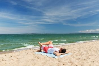summer holidays and people concept - happy smiling young man sunbathing on beach towel. happy smiling young man sunbathing on beach towel