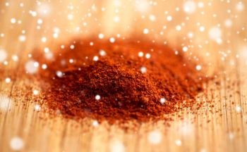 cooking, spice and ethnoscience concept - cayenne, chili pepper or paprika powder on wood over snow. cayenne pepper or paprika powder on wood