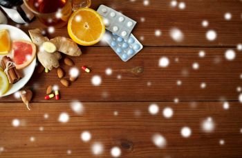 healthcare and ethnoscience concept - traditional medicine and drug pills on wooden table over snow. traditional medicine and drugs