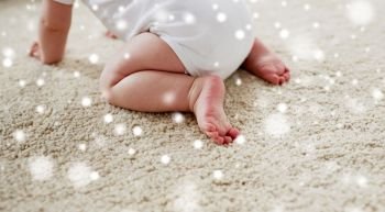 childhood, babyhood and people concept - little baby boy or girl crawling on floor over snow. little baby in diaper crawling on floor