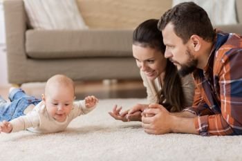 family, parenthood and people concept - happy mother and father playing with baby at home. happy family playing with baby at home