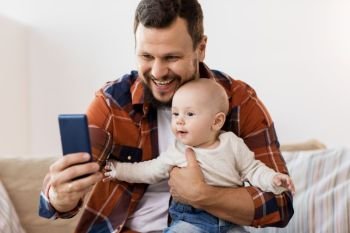 family, parenthood and people concept - happy father with little baby boy taking selfie at home. happy father with baby boy taking selfie at home