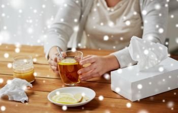health, traditional medicine and ethnoscience concept - close up of ill ill woman drinking tea with lemon over snow. close up of ill woman drinking tea with lemon