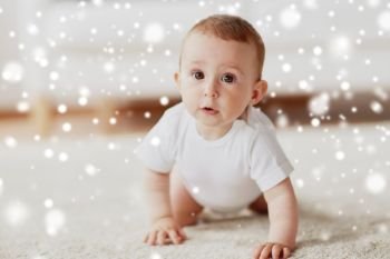 childhood, babyhood and people concept - happy little baby boy or girl crawling on floor at home over snow. little baby in diaper crawling on floor at home