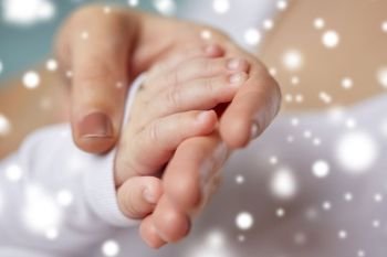 family, motherhood, people and child care concept - close up of mother and newborn baby hands over snow. close up of mother and newborn baby hands