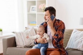 family, parenthood and people concept - father with little baby boy calling on smartphone at home. father with baby calling on smartphone at home