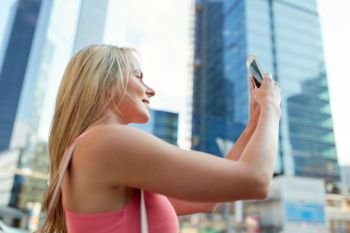 women and people concept - happy smiling young woman with smartphone photographing city. young woman with smartphone photographing city