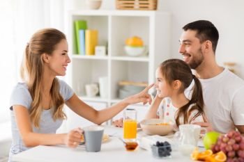 family, eating and people concept - happy mother, father and daughter having breakfast at home. happy family having breakfast at home