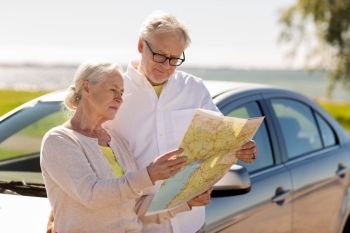 road trip, travel and old people concept - senior couple with car looking for location on map in summer. senior couple with car looking for location on map
