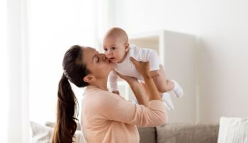 family, motherhood and people concept - happy mother kissing little baby boy at home. happy mother kissing little baby boy at home