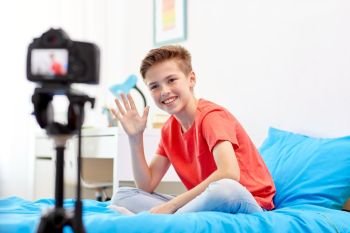blogging, technology and people concept - happy smiling boy or blogger with camera recording video at home. happy boy with camera recording video at home