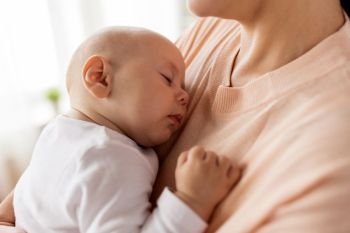 family, motherhood and people concept - close up of mother holding sleeping little baby boy. close up of mother holding sleeping baby