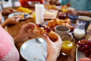 food, baking and people concept - hands of woman eating croissant for breakfast at table. hands of woman eating croissant for breakfast
