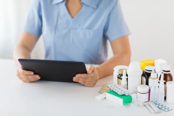 medicine, healthcare and technology concept - nurse or doctor with drugs and tablet pc computer at hospital. nurse or doctor with medicines and tablet pc